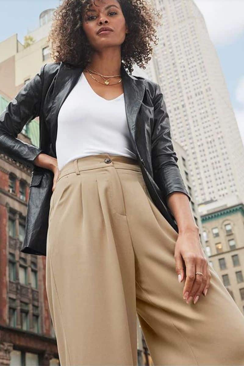 Leather Clothes are Trending: Here's How to Wear Them 6 Model looking down at camera wears leather blazer, white top, and beige trousers.