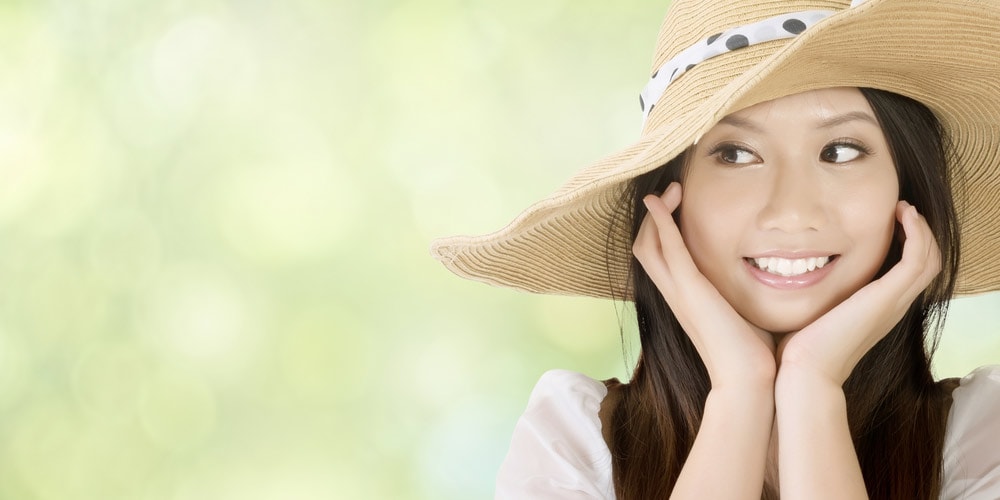 Smiling woman wearing floppy hat outside