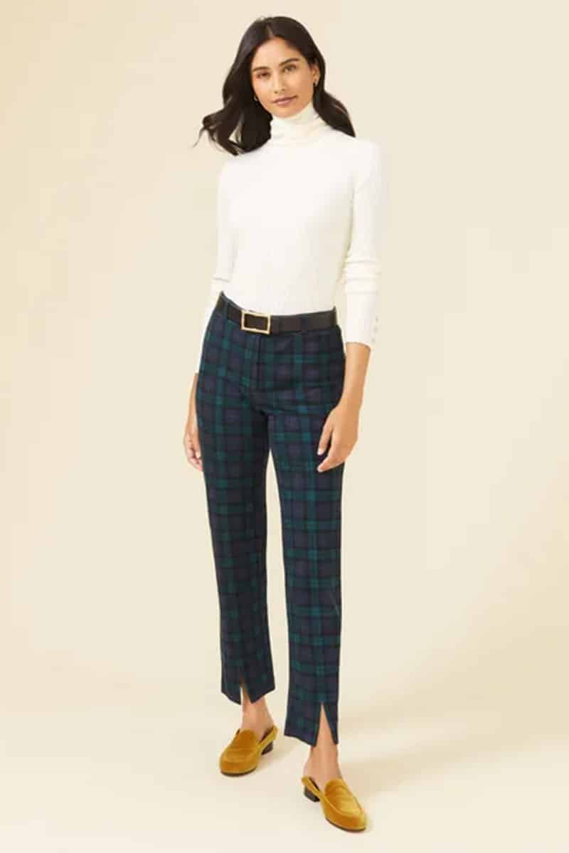 Model wears tartan pants against cream background. 