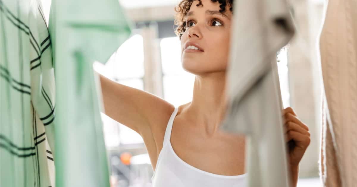 The Style Trends to Keep and Drop 56 Woman looks through closet at home.