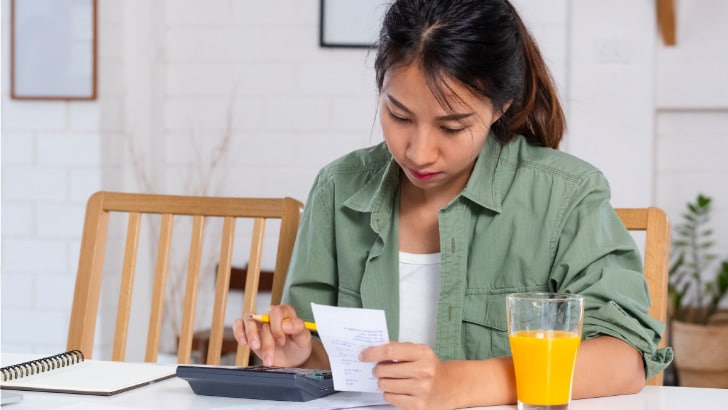 Clothing Inflation: 6 Ways to Stay Stylish as Prices Rise 12 Woman works on household budget because of clothing inflation.