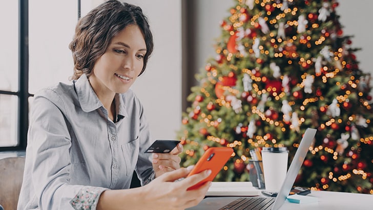 Holiday Shoppers Ask: How Can I Save Money? Here Are the Answers 9 Woman shops online for holiday gifts.