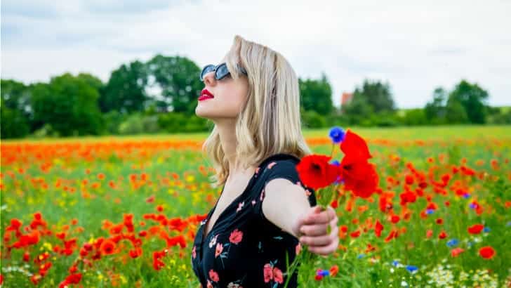 10 Essential Summer Dress Styles 89 Woman wearing summer dress style stands in filed of flowers.