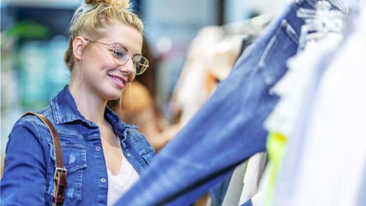 What to Buy at Thrift Stores: 5 Product Categories to Shop Secondhand 90 Woman smiles shopping in thrift store.