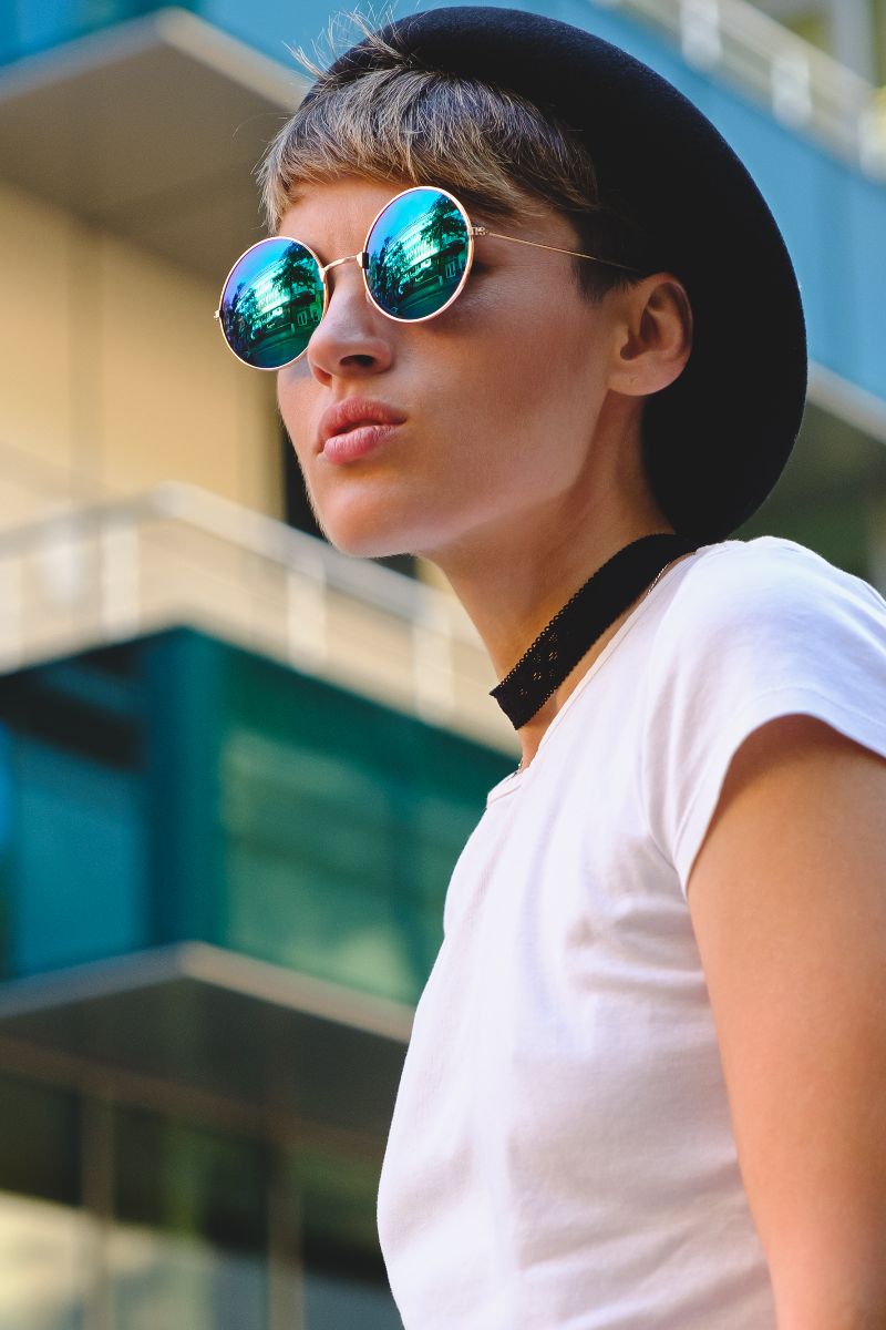 What Kind of Sunglasses to Buy 2 Side view of woman wearing round sunglasses and hat.