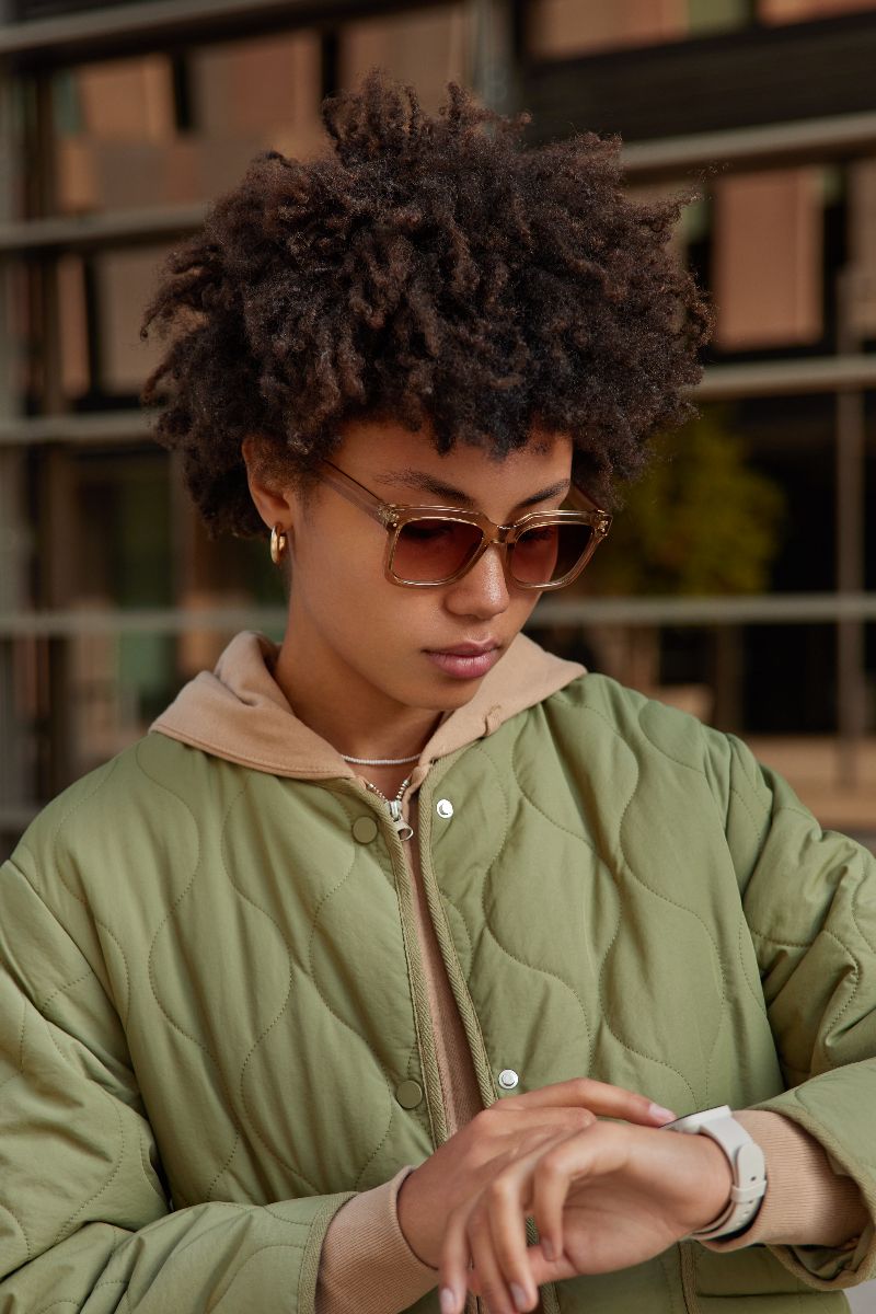 What Kind of Sunglasses to Buy 3 Woman wearing color-coordinated sunglasses looks at her watch.