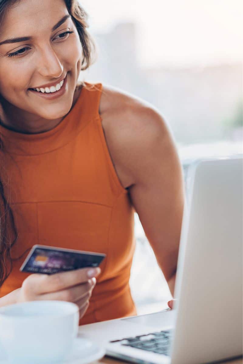 Farfetch Sale: 10 Designer Pieces to Shop Now for Less 1 Woman shops Farfetch sale on her laptop.