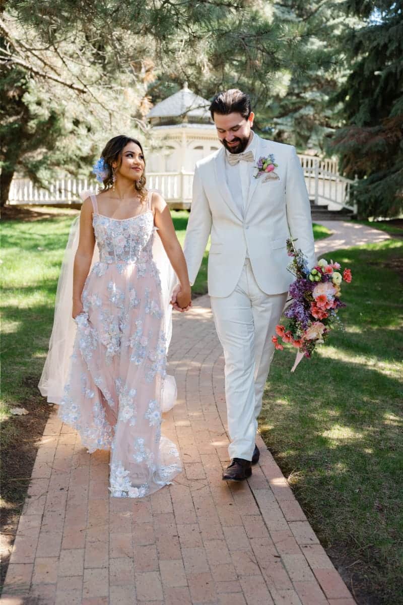 Buying Bridesmaid Dresses Online: 11 Tips for Success 4 Couple wearing bridal attire walks together outside.
