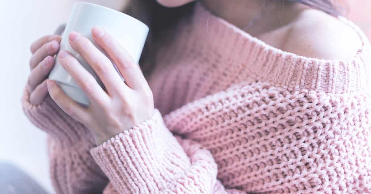 Cozy Girl Style: The Scoop on the TikTok Fashion Trend 62 Woman wearing cozy sweater and holding a mug.
