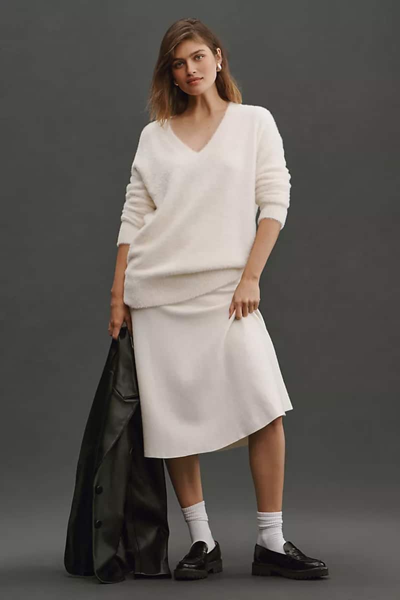 Cozy Girl Style: The Scoop on the TikTok Fashion Trend 3 Model wears v-neck top with midi skirt and holds jacket.