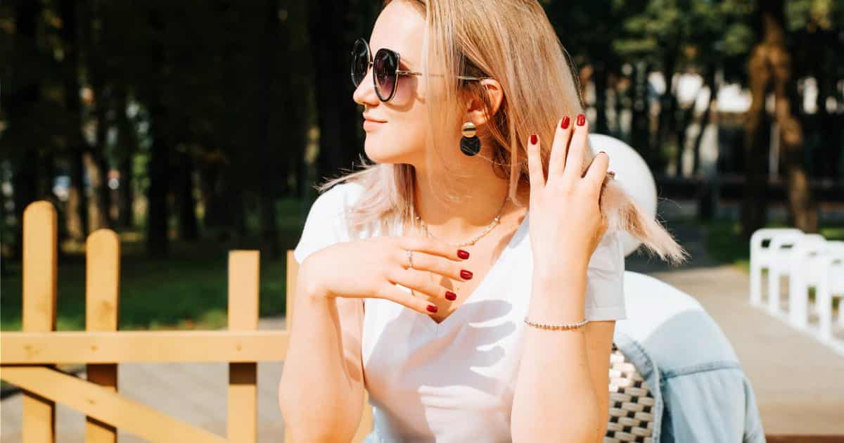 6 Gel Nail Alternatives for Your Best Manicure 58 Woman sitting outside with pretty red manicure.