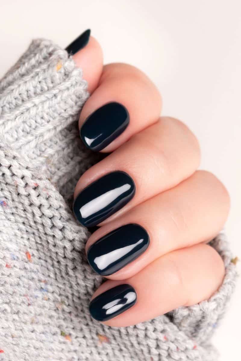 Woman's hand with dark-colored gel manicure.
