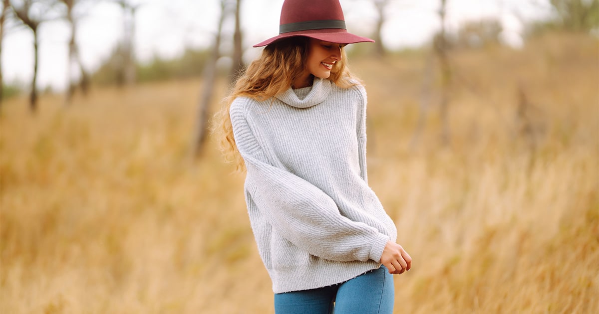 10 Wool Sweater Outfit Ideas for Cozy, Chic Style in 2024 52 Woman smiling wearing sweater outside in field.