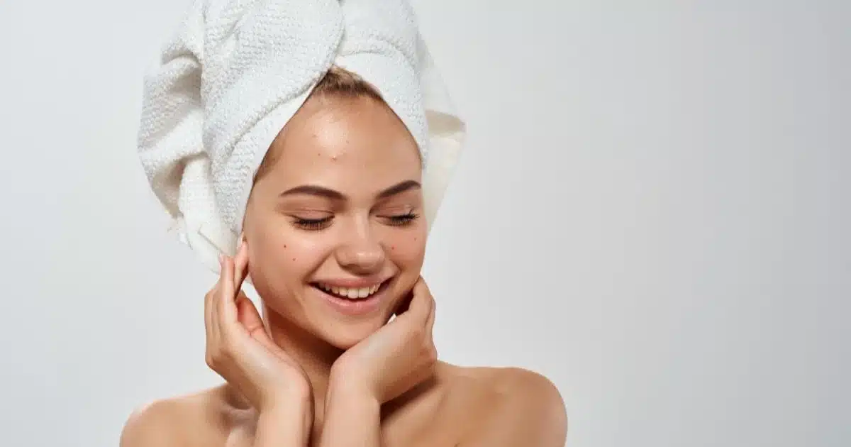Fading Acne Scars: 14 Best Treatment Options 50 Smiling woman with acne wearing a towel on her head.