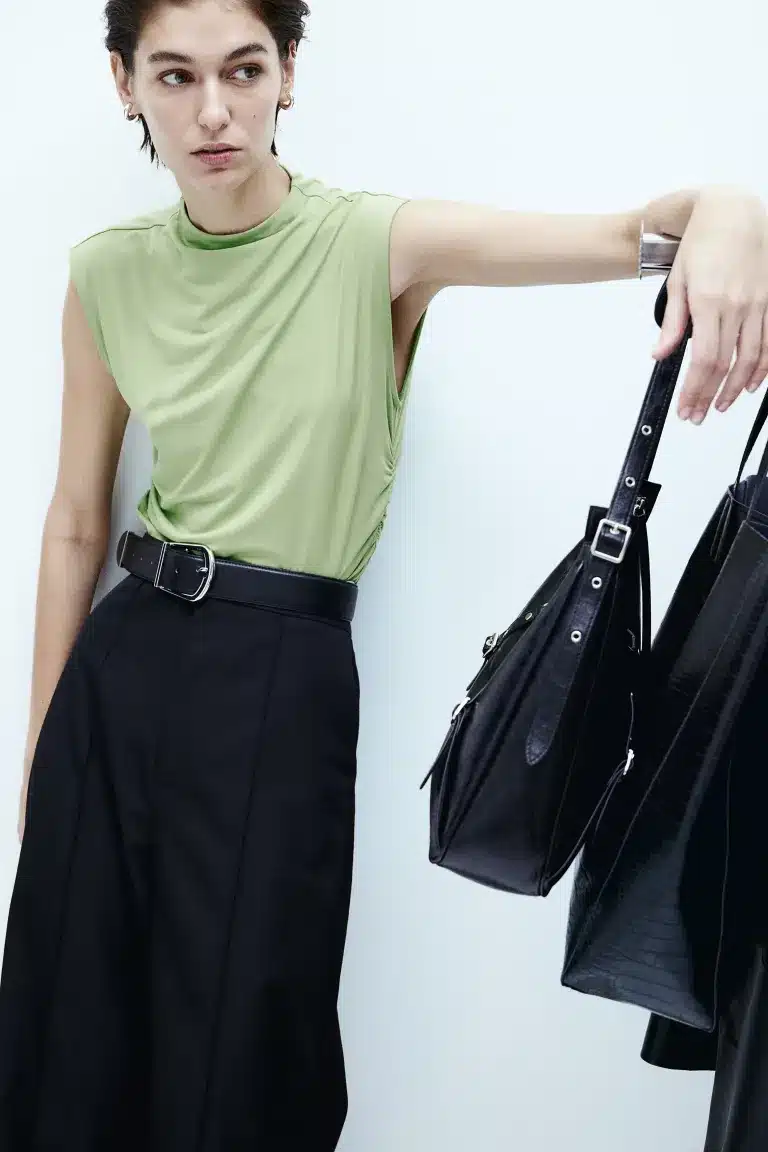 Spring 2024 Fashion Trends: 36 Trendy, Affordable Pieces to Wear Now 8 Model wears mint green crop top with black pants and holds handbag.