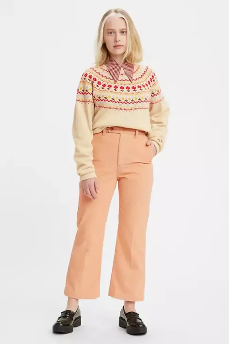 How to Wear the Color Peach 22 Model wearing peach pants in front of gray background.