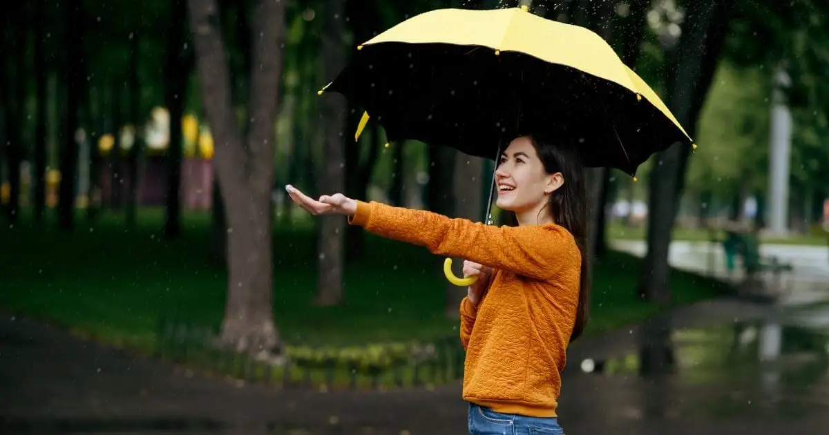 7 Ways to Waterproof Your Spring Look Under $50 39 Woman standing out in rain with umbrella.