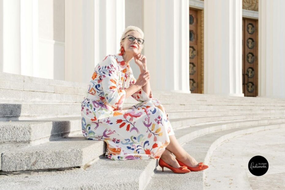 Old woman in floral dress sitting on steps.